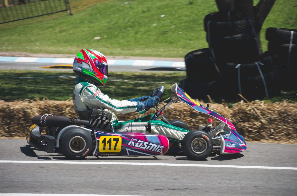 Homme en combinaison de course avec casque faisant du karting